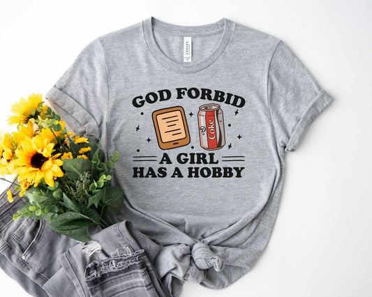 A bella canvas 3001 shirt with the saying "god forbid a girl has a hobby"