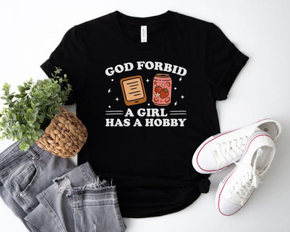 A bella canvas 3001 shirt with the saying "god forbid a girl has a hobby"