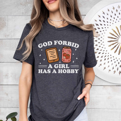 A bella canvas 3001 shirt with the saying "god forbid a girl has a hobby"