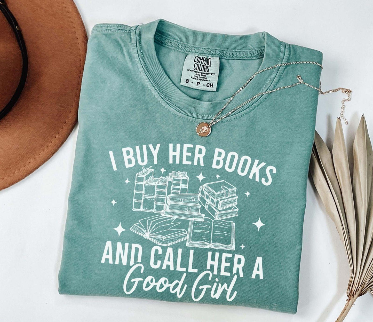 A comfort colors shirt with the saying "I buy her books and call her a good girl"