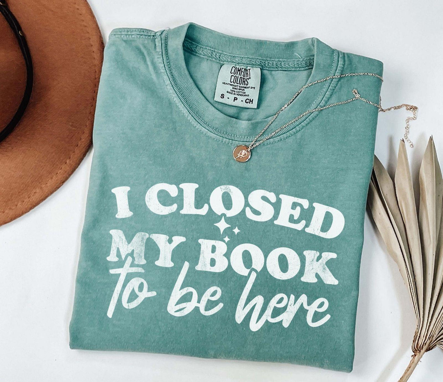 A comfort colors shirt with the saying "I closed my book to be here"