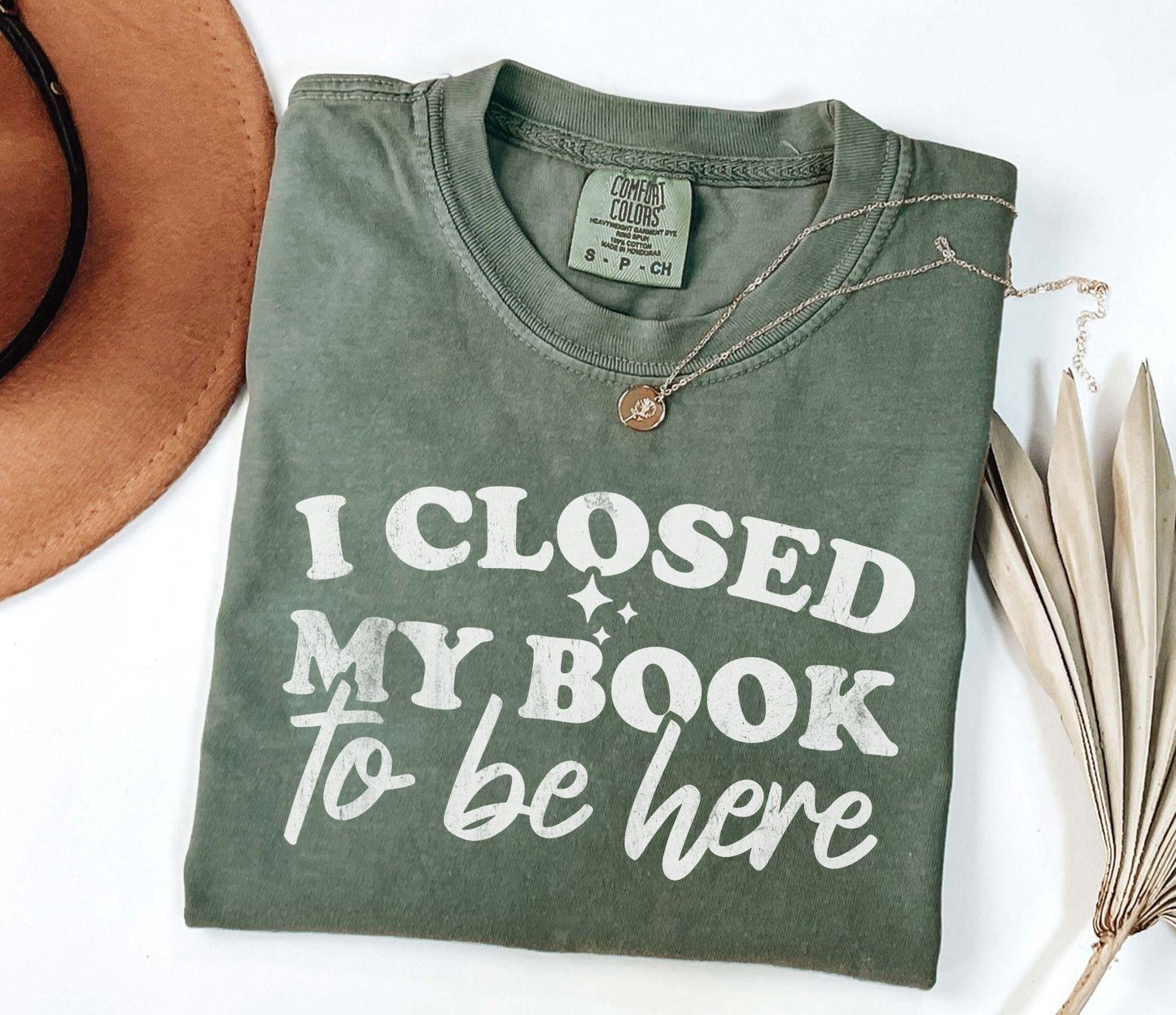 A comfort colors shirt with the saying "I closed my book to be here"