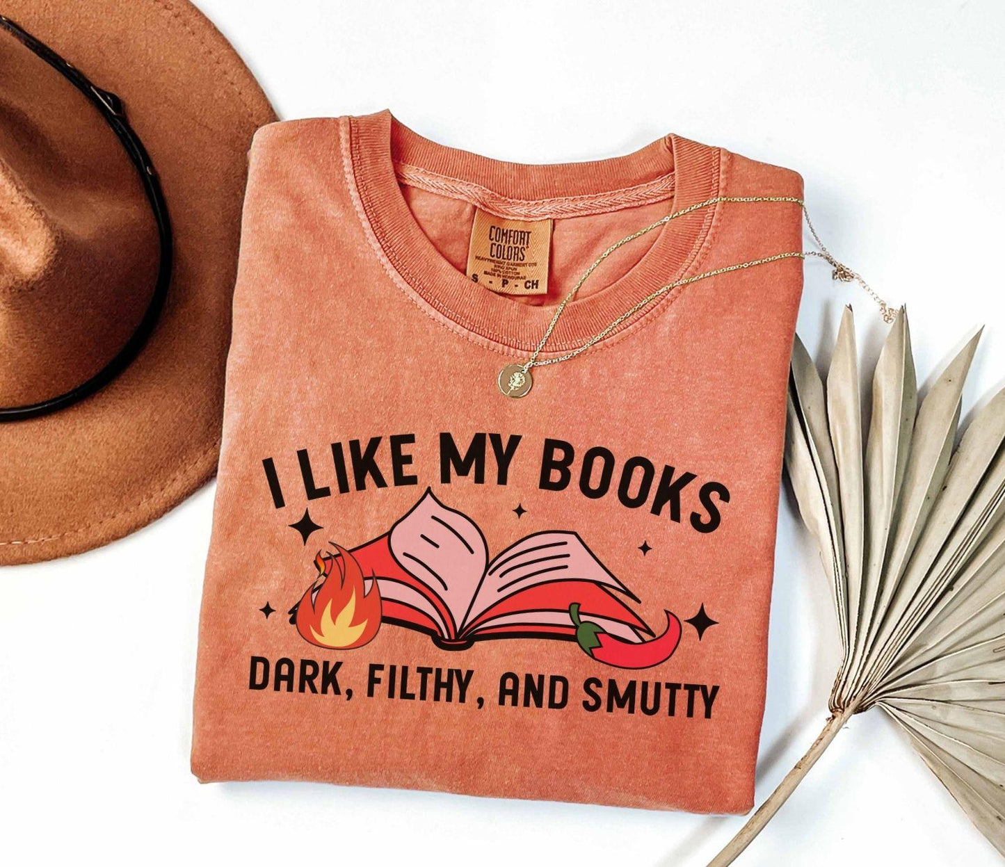 A comfort colors shirt with the saying "I like my books dark filthy and smutty"