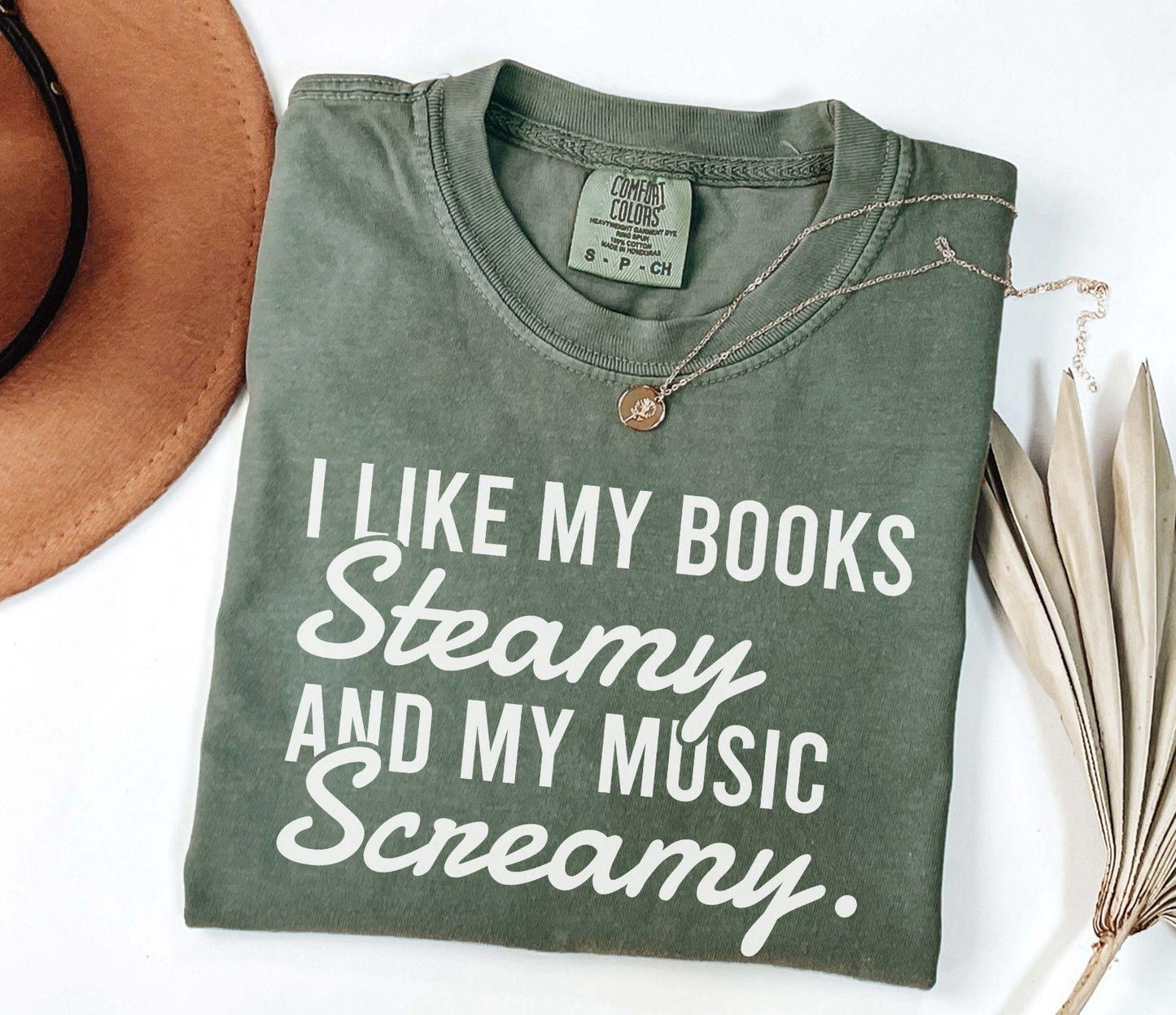 A comfort colors shirt with the saying "I like my books steamy and my music screamy"