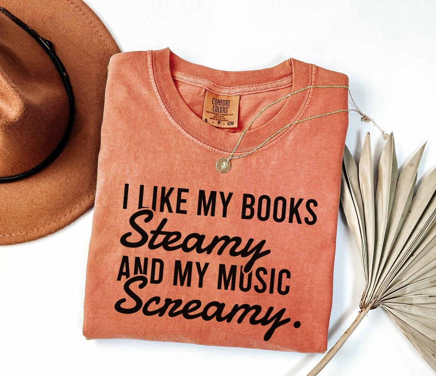 A comfort colors shirt with the saying "I like my books steamy and my music screamy"