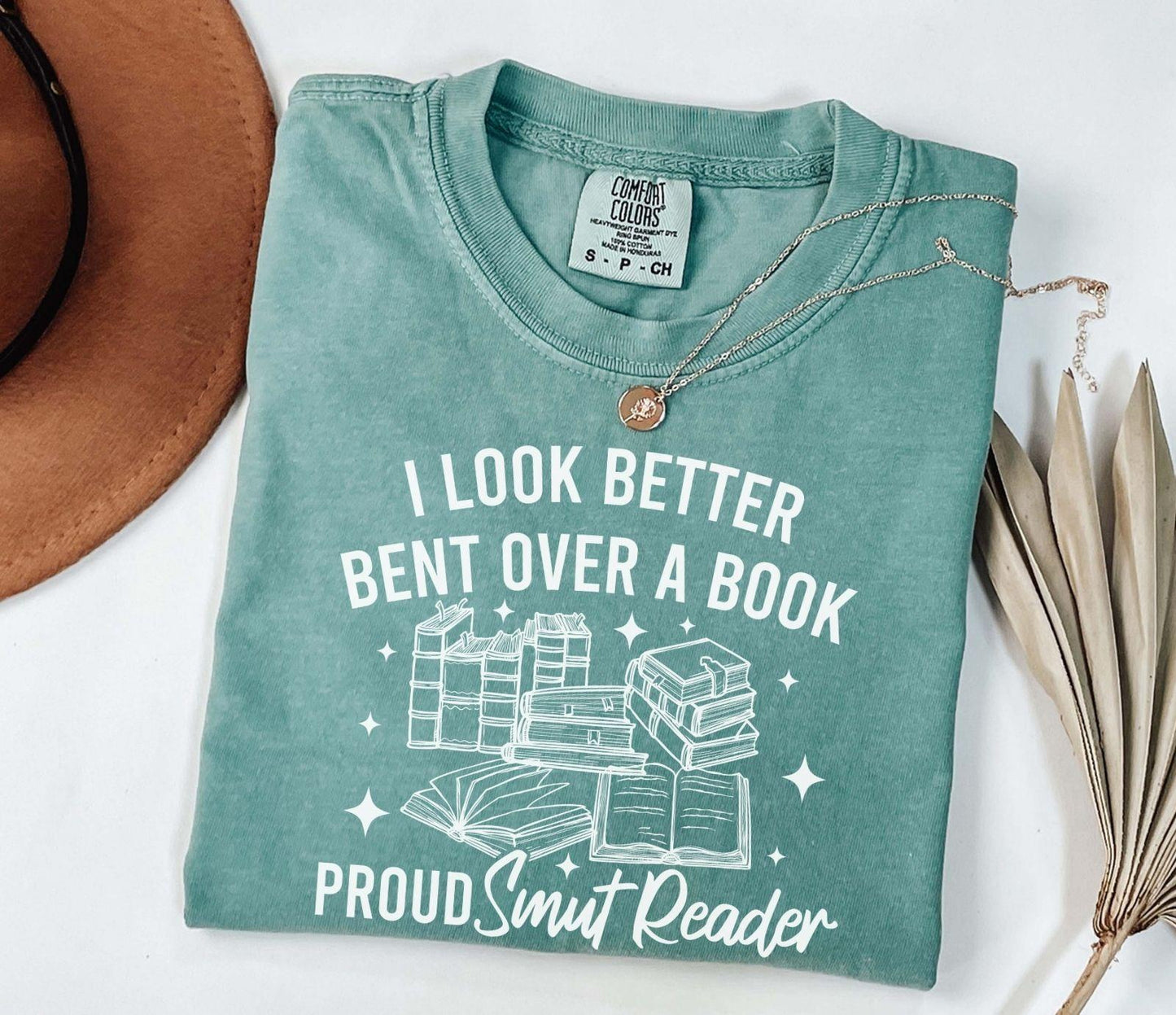 A comfort colors shirt with the saying "I look better bent over a book proud smut reader"