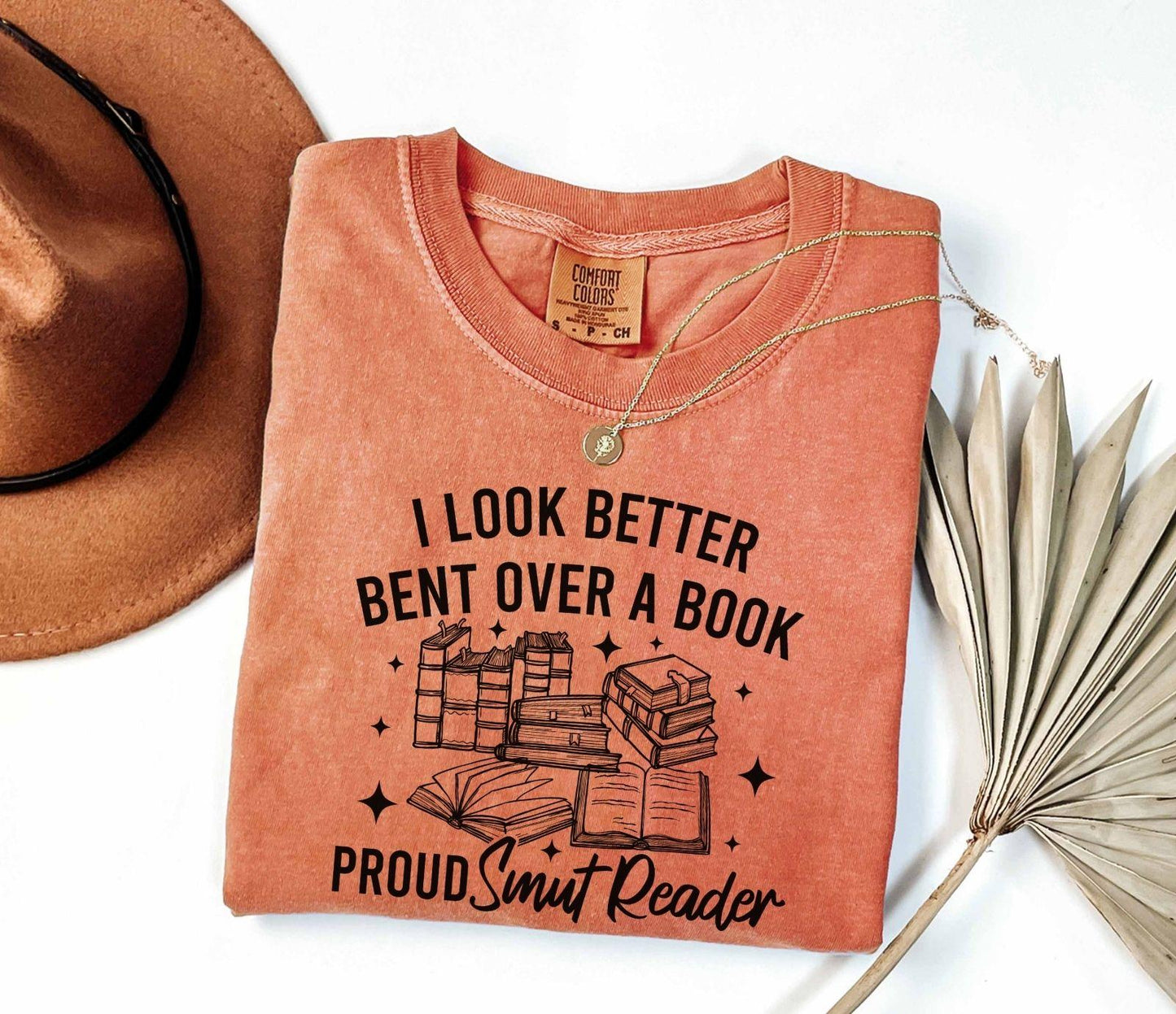 A comfort colors shirt with the saying "I look better bent over a book proud smut reader"
