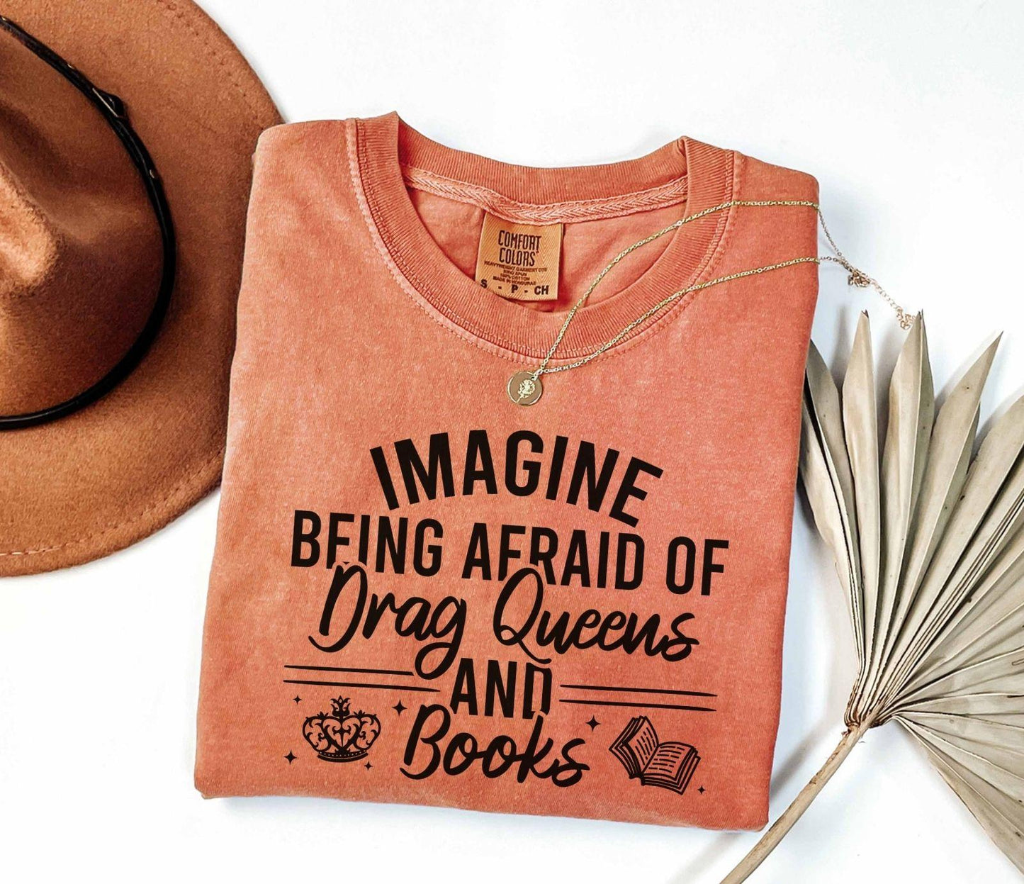 A comfort colors shirt with the saying "Imagine being afraid of drag queens and books"