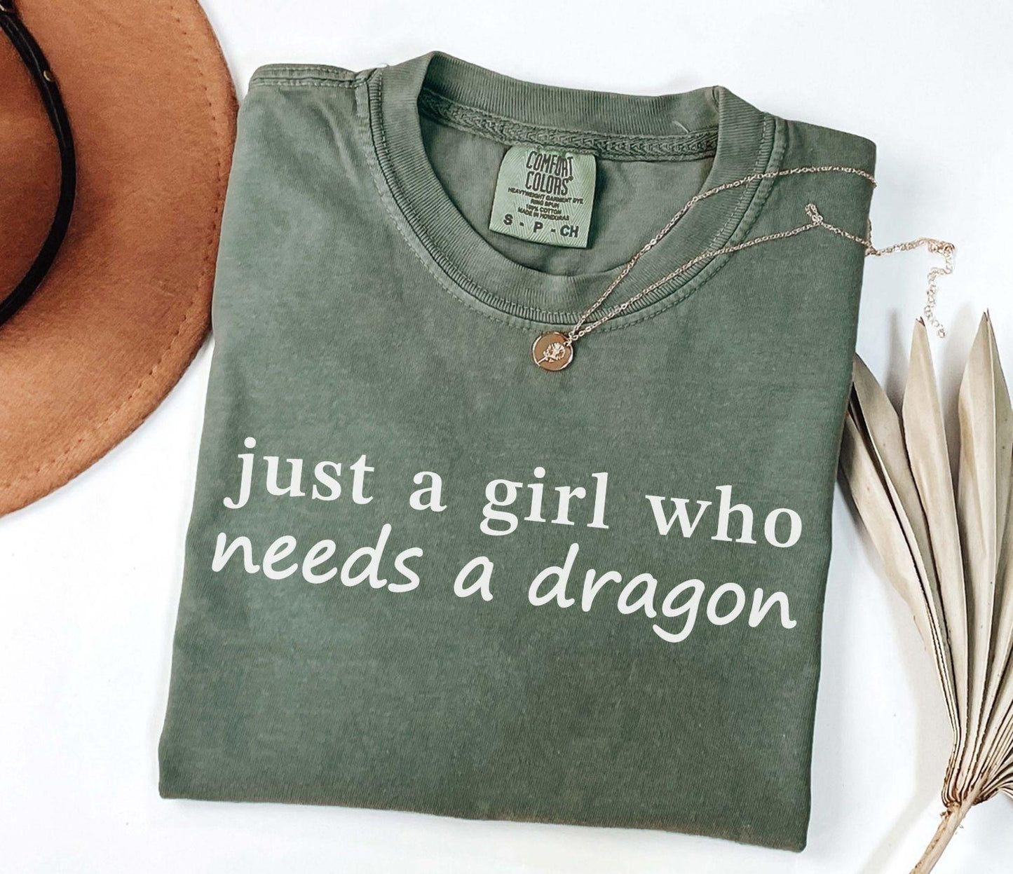 A comfort colors® shirt with the saying "just a girl who needs a dragon"