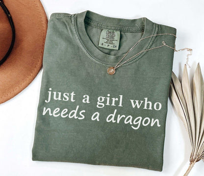 A comfort colors® shirt with the saying "just a girl who needs a dragon"