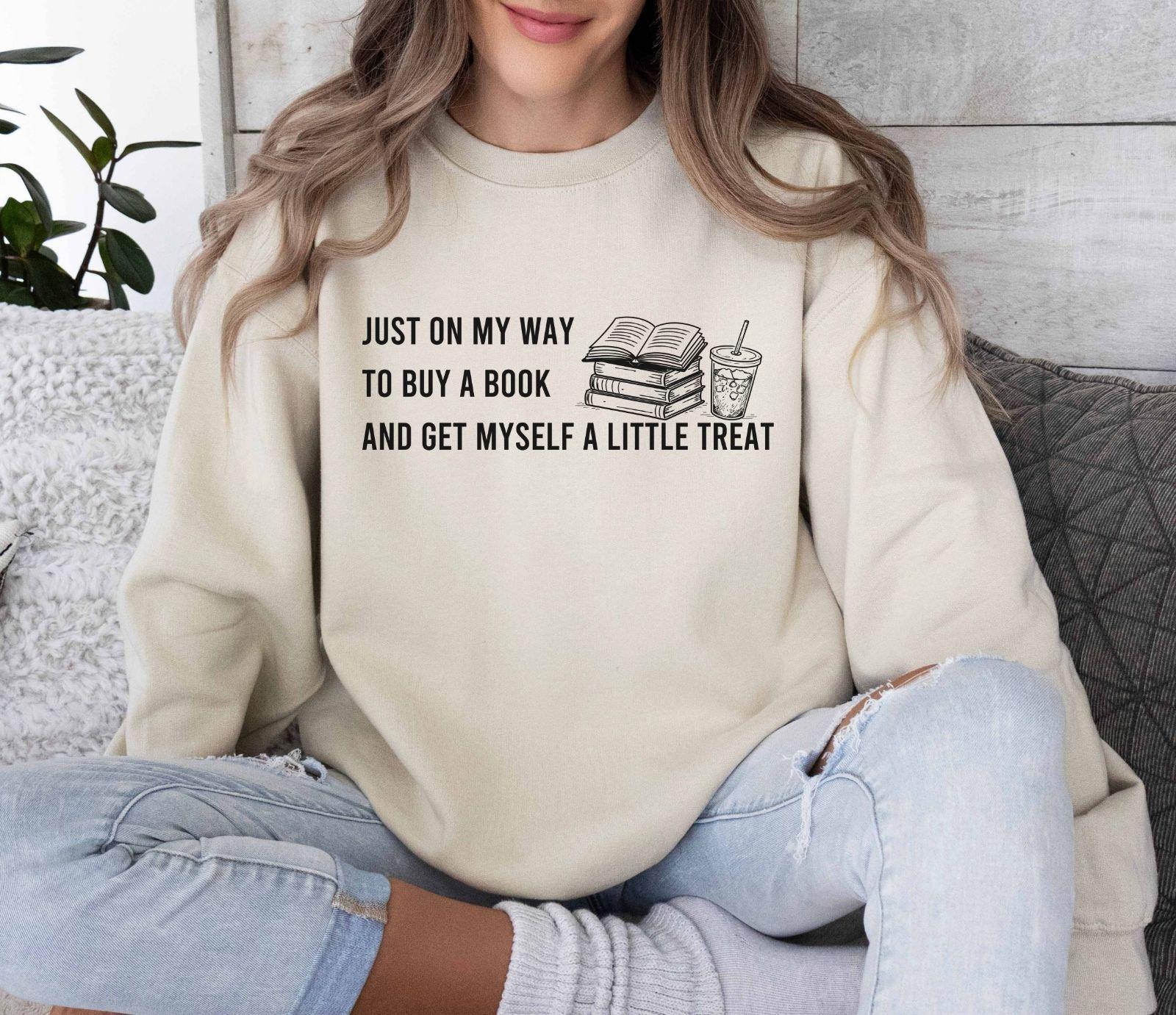 A dark heather color Gildan 18000 sweatshirt with the saying "Just on my way to buy a boook and get myself a little treat"