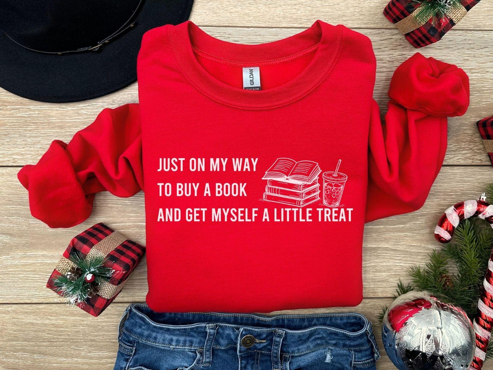 A dark heather color Gildan 18000 sweatshirt with the saying "Just on my way to buy a boook and get myself a little treat"