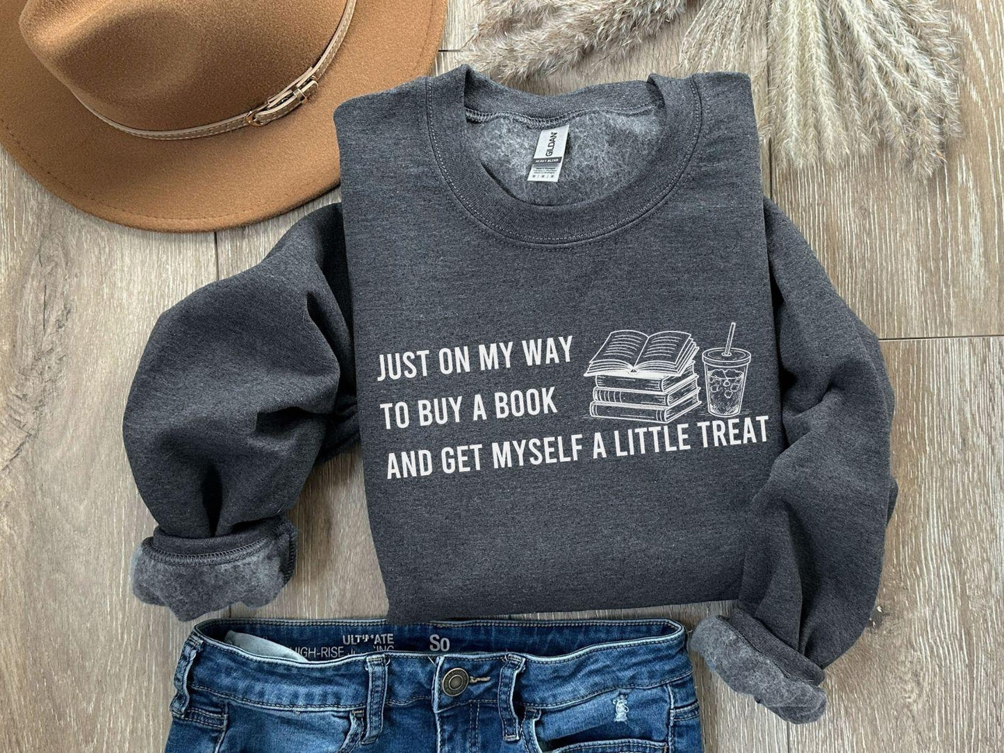 A dark heather color Gildan 18000 sweatshirt with the saying "Just on my way to buy a boook and get myself a little treat"