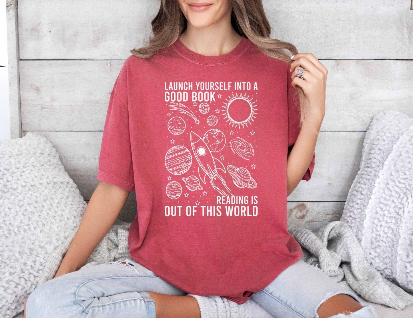 A comfort colors® shirt with the saying "launch yourself into a good book reading is out of this world"