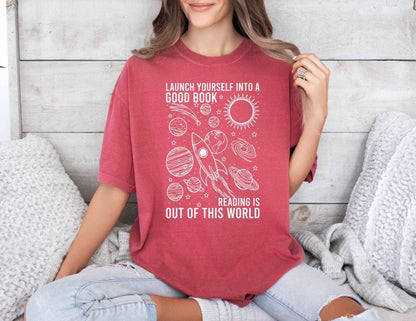 A comfort colors® shirt with the saying "launch yourself into a good book reading is out of this world"