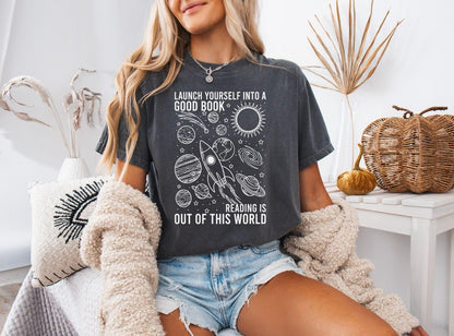 A comfort colors® shirt with the saying "launch yourself into a good book reading is out of this world"