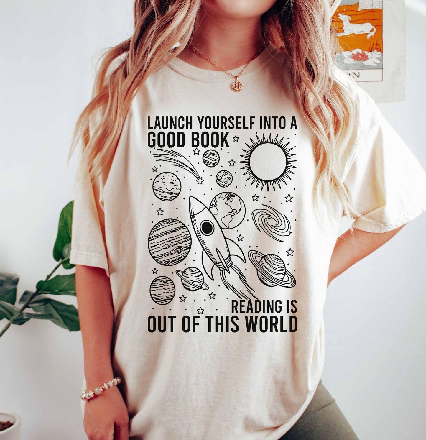 A comfort colors® shirt with the saying "launch yourself into a good book reading is out of this world"