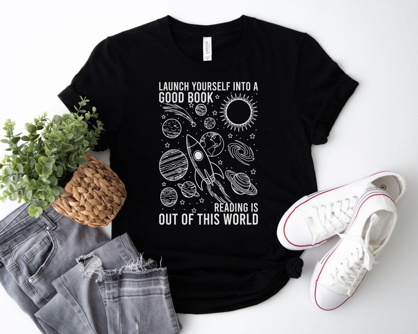 A bella canvas 3001 shirt with the saying "launch yourself into a good book reading is out of this world"