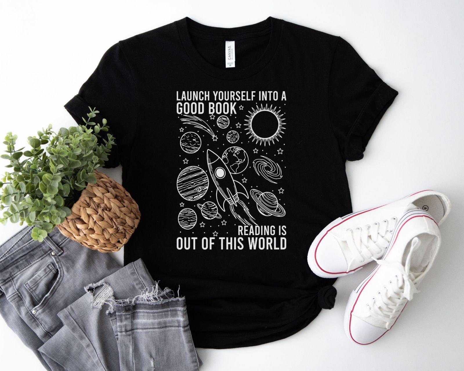 A bella canvas 3001 shirt with the saying "launch yourself into a good book reading is out of this world"