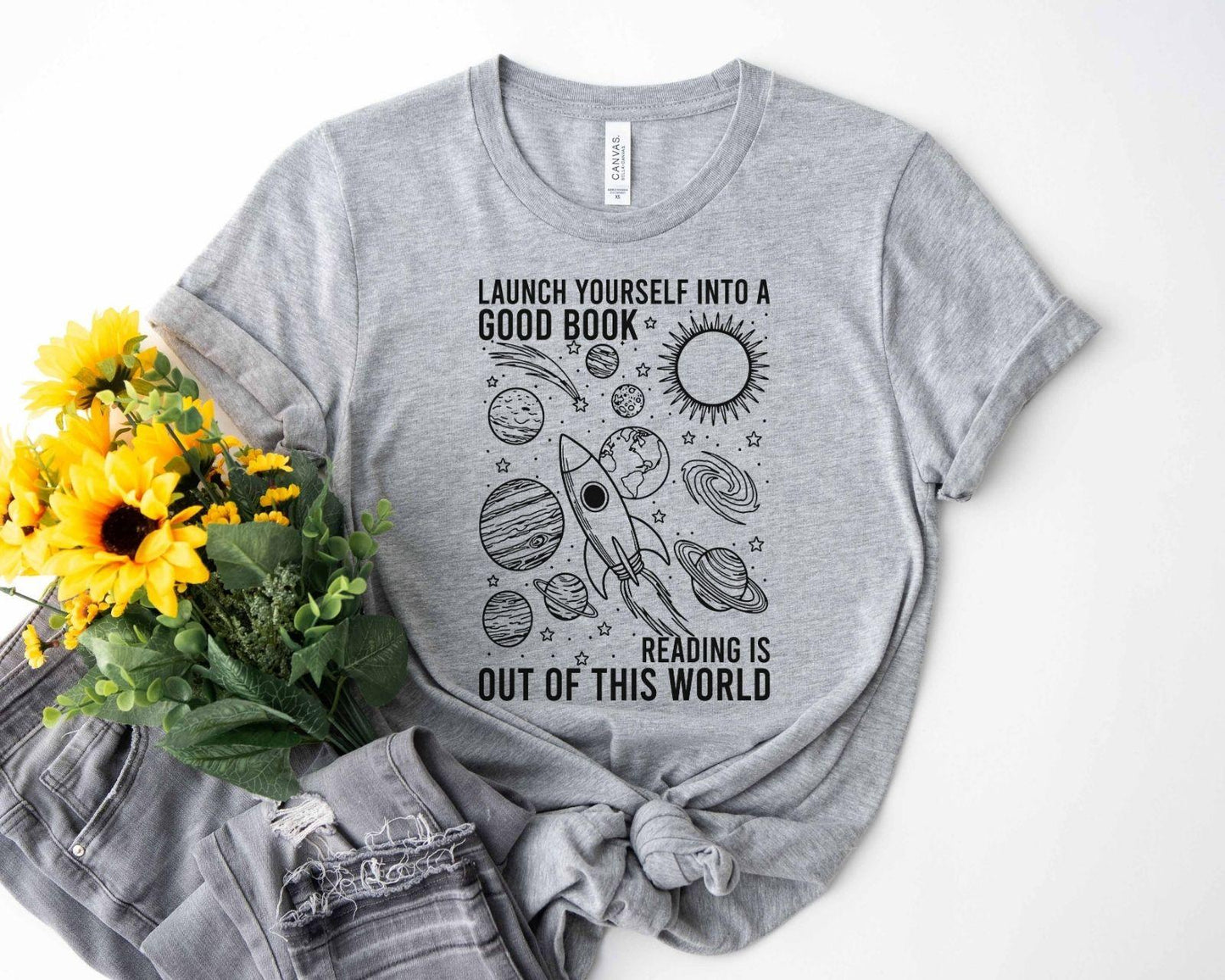 A bella canvas 3001 shirt with the saying "launch yourself into a good book reading is out of this world"