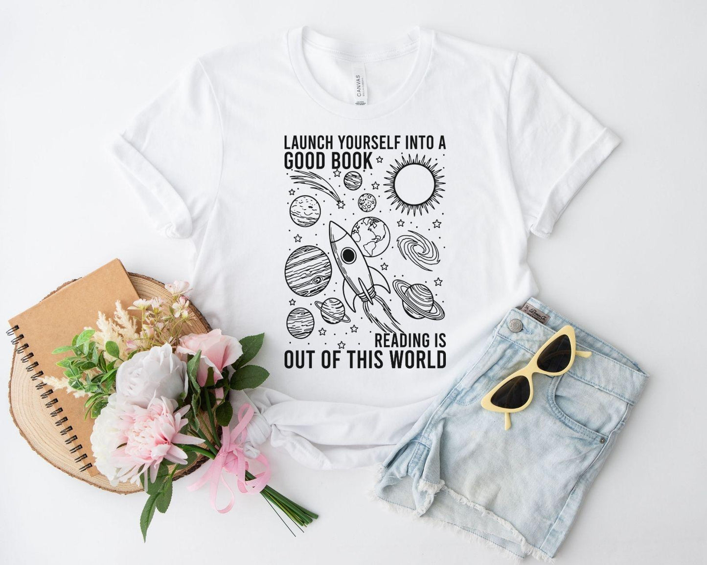 A bella canvas 3001 shirt with the saying "launch yourself into a good book reading is out of this world"