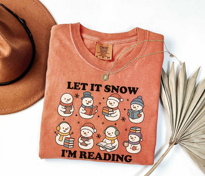 A comfort colors shirt with the saying "Let it snow I'm reading"
