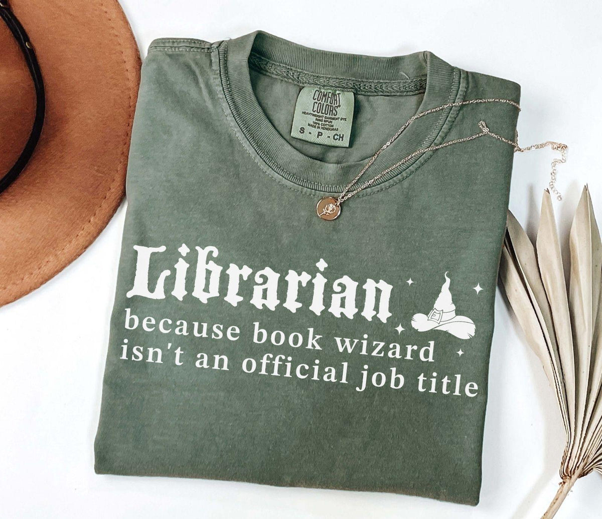 A comfort colors® shirt with the saying "librarian because book wizard isn't an official job title"