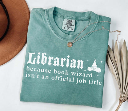 A comfort colors® shirt with the saying "librarian because book wizard isn't an official job title"
