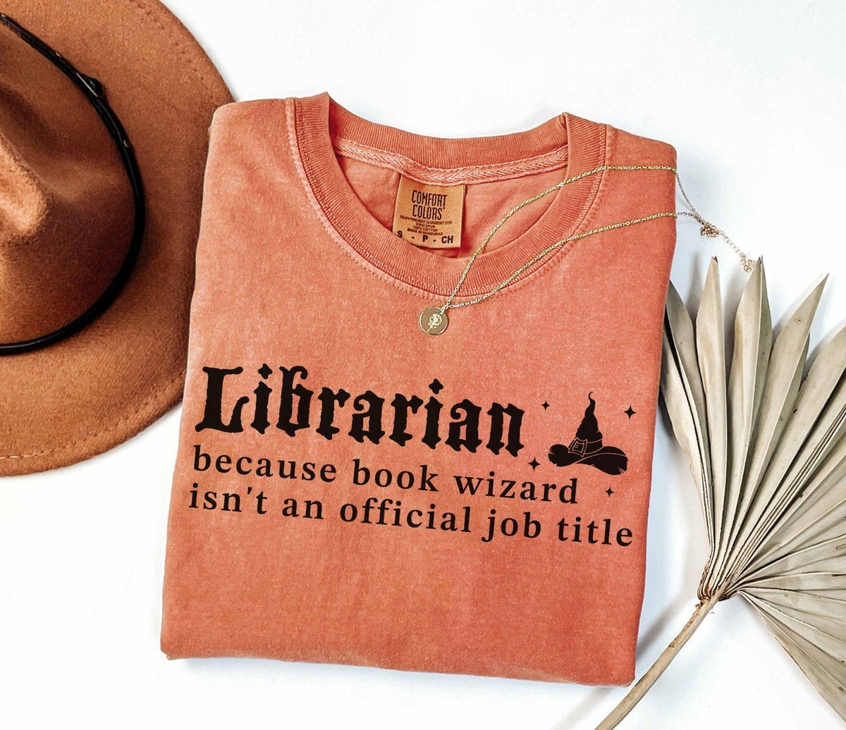 A comfort colors® shirt with the saying "librarian because book wizard isn't an official job title"