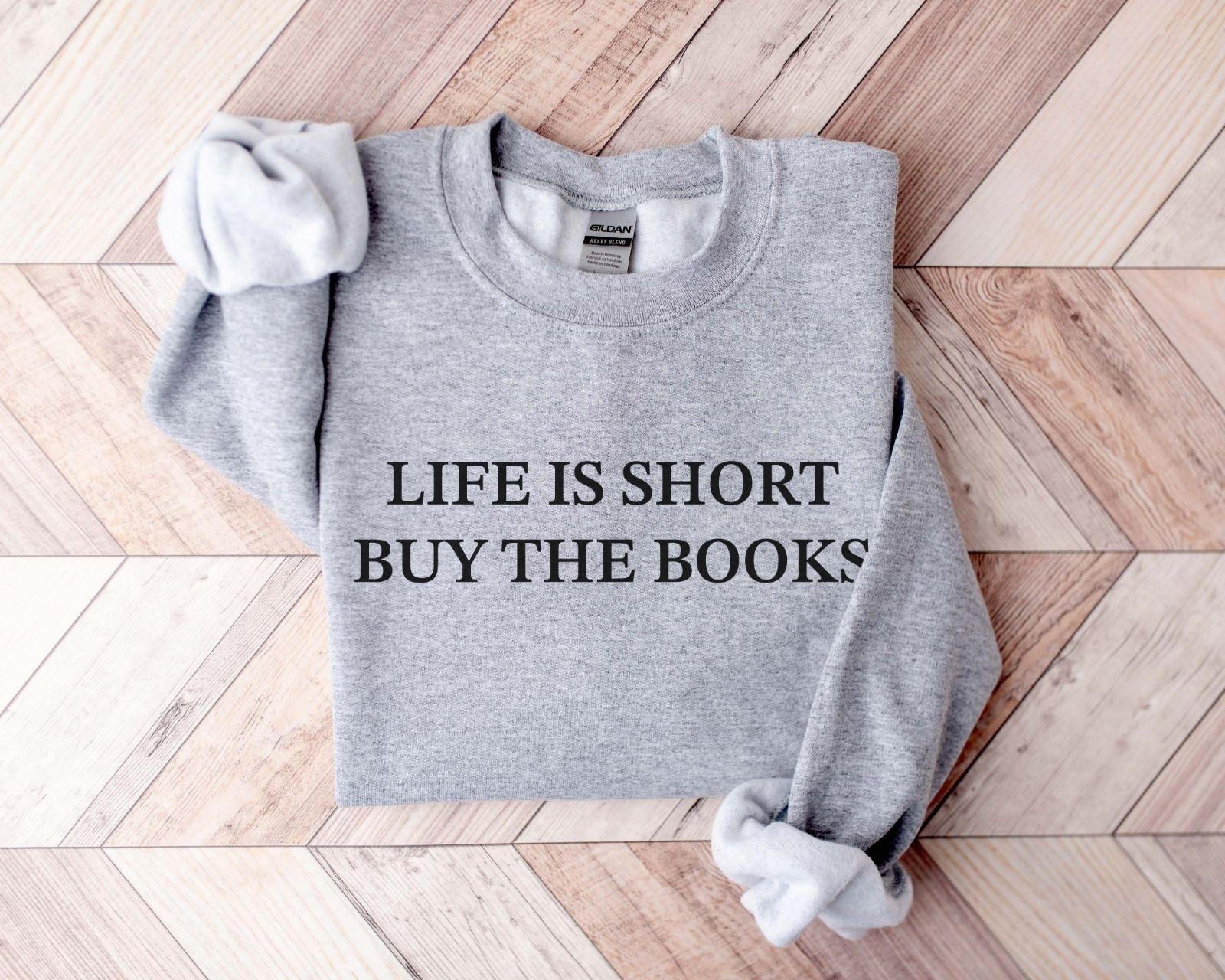 A Gildan 18000 sweatshirt with the saying "life is short buy the books"