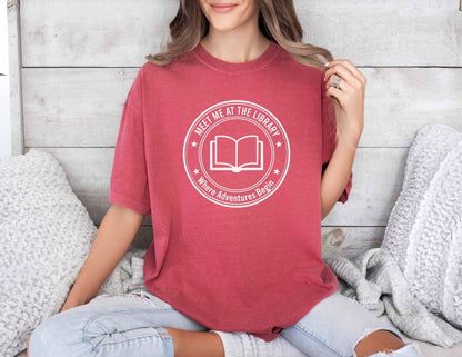 A comfort colors® shirt with the saying "meet me at the library where adventure begin"