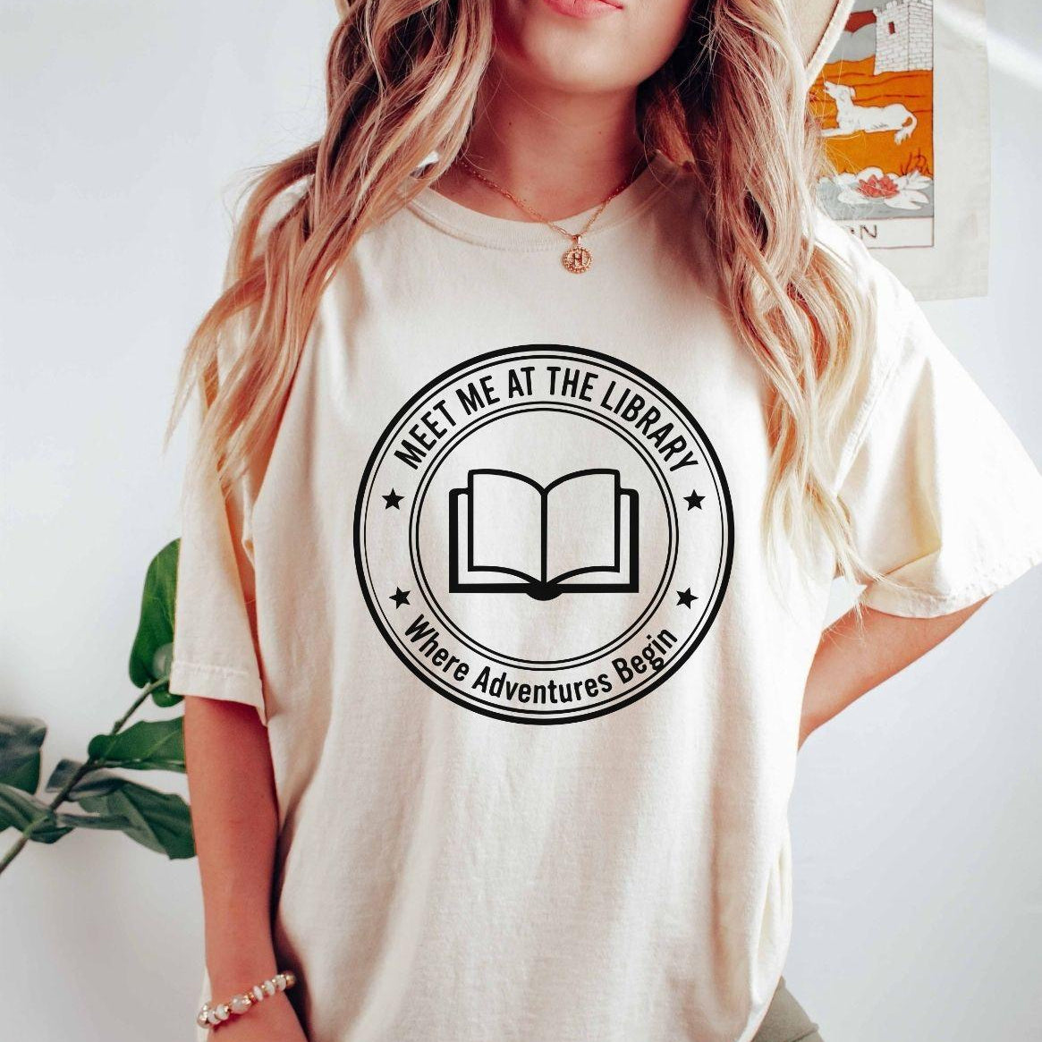 A comfort colors® shirt with the saying "meet me at the library where adventure begin"