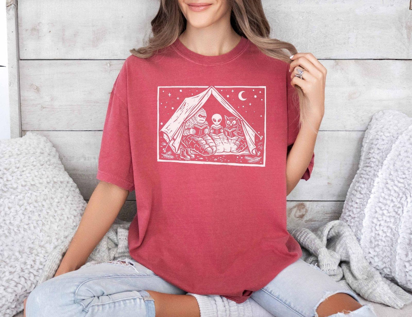 A comfort colors® shirt with the saying "Mothman Bigfoot and Horned reading a book"