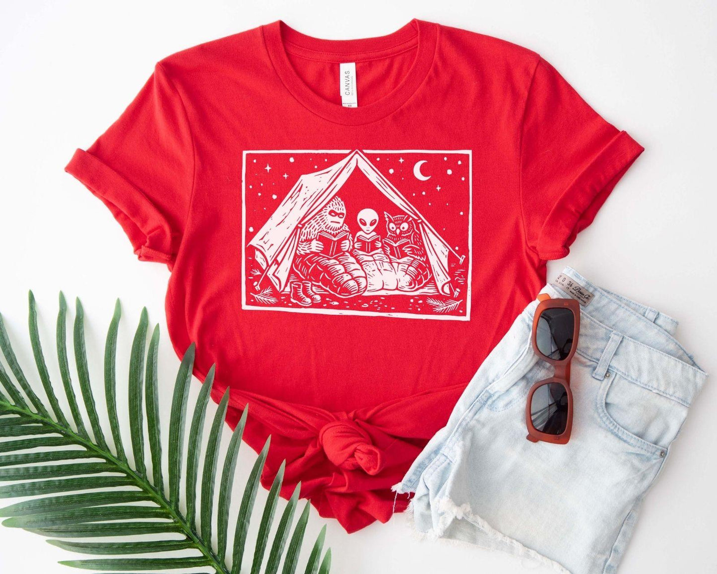 A bella canvas 3001 shirt with the saying "mothman, bigfoot and horned reading books"
