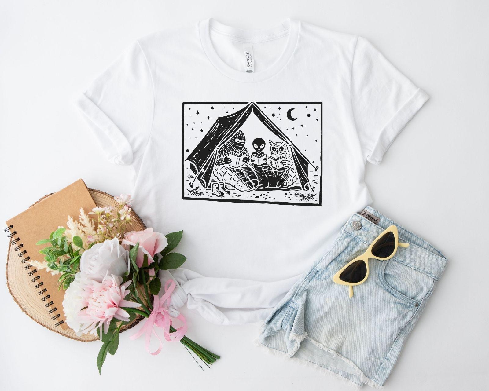 A bella canvas 3001 shirt with the saying "mothman, bigfoot and horned reading books"