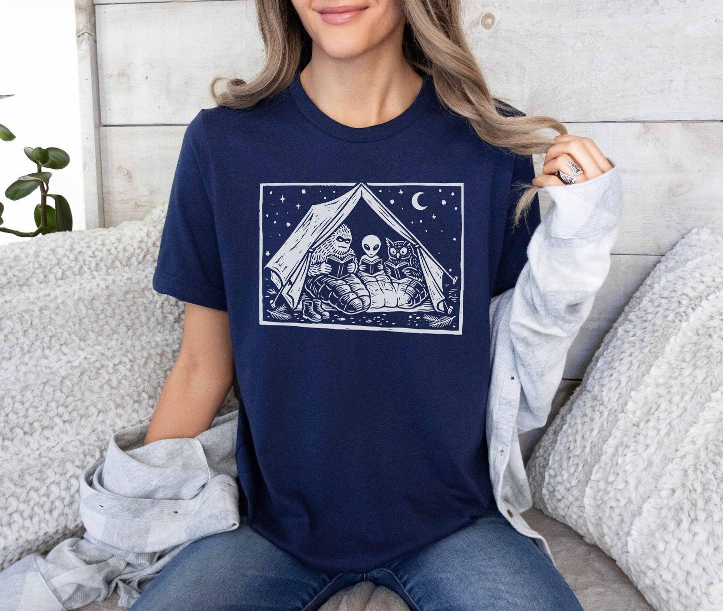 A bella canvas 3001 shirt with the saying "mothman, bigfoot and horned reading books"