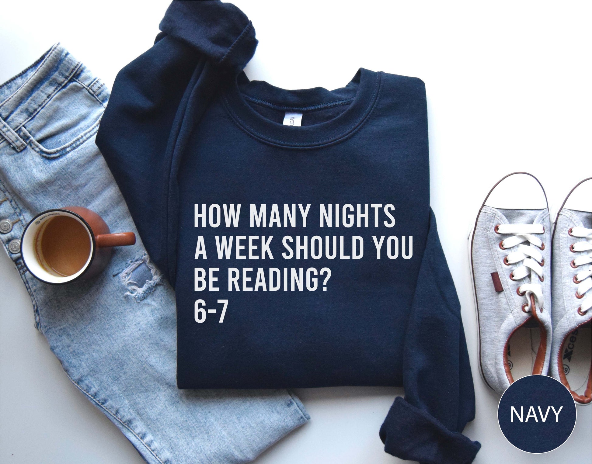 Navy sweatshirt with text, jeans, mug, and shoes on a white background