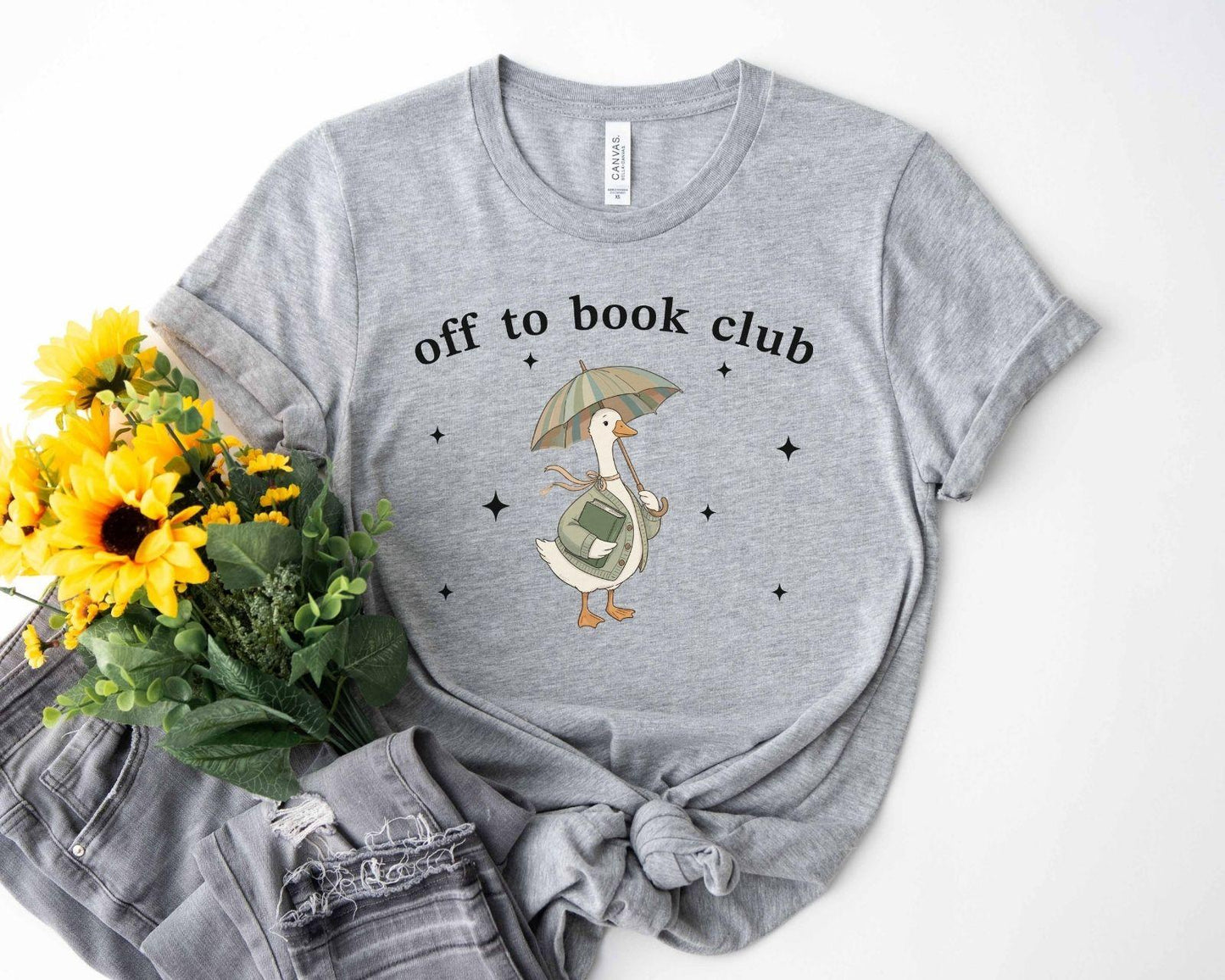A bella canvas 3001 shirt with the saying "off to book club"