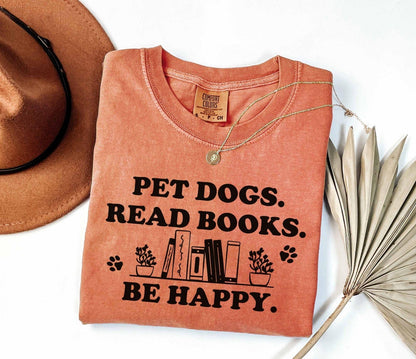 A comfort colors shirt with the saying "Pet dogs read books be happy"