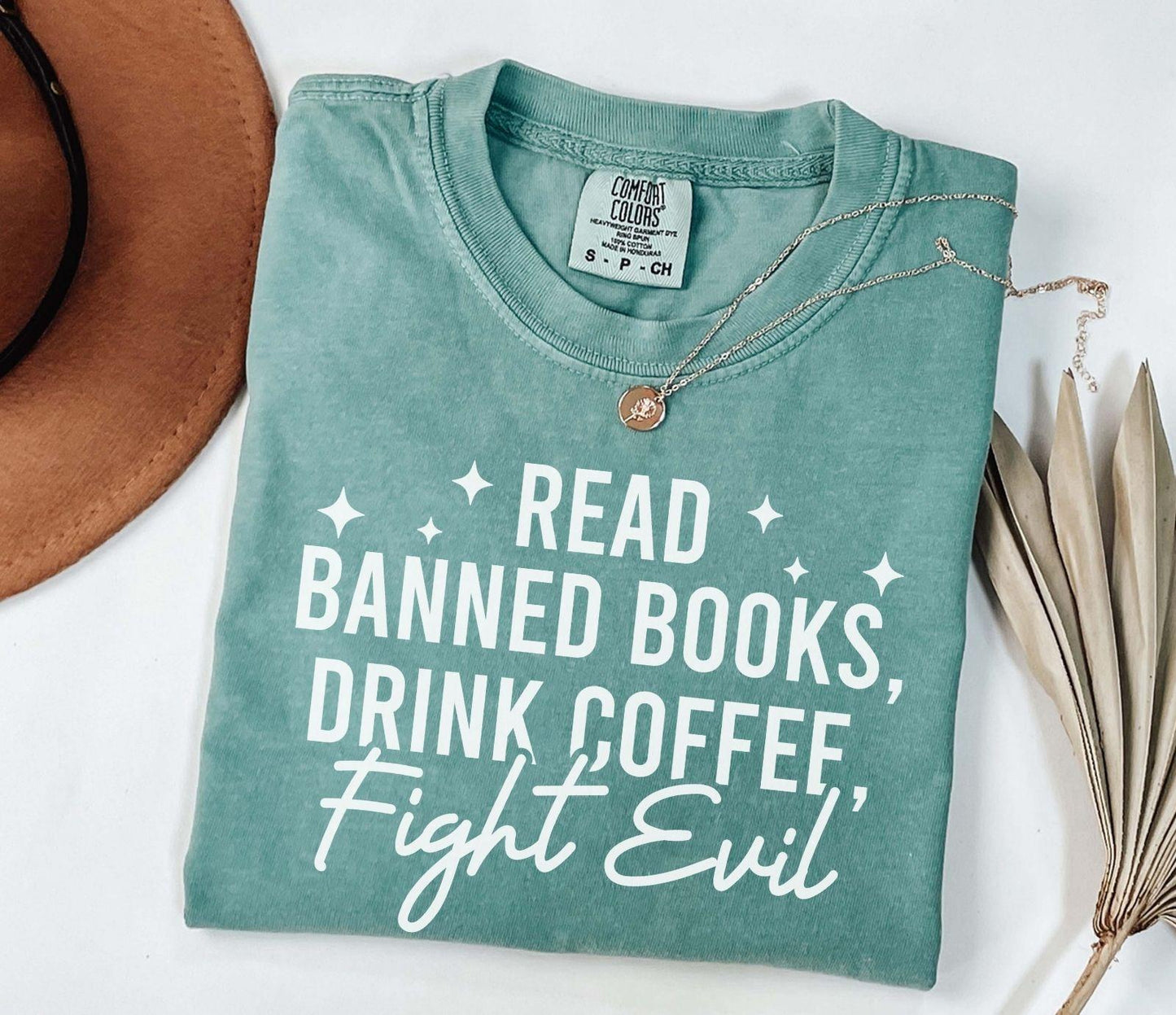 A comfort colors shirt with the saying "Read banned books drink coffee fight evil"