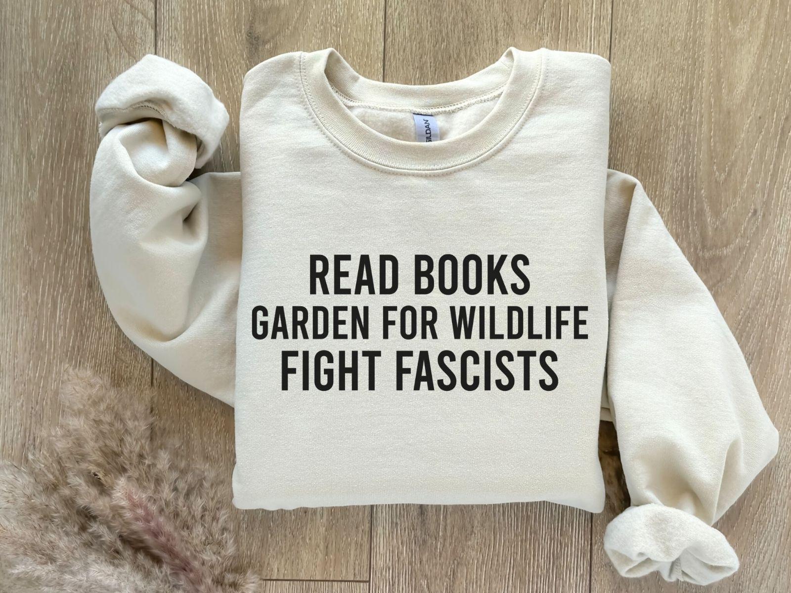 A Gildan 18000 sweatshirt with the saying "Read books garden for wildlife fight fascists"