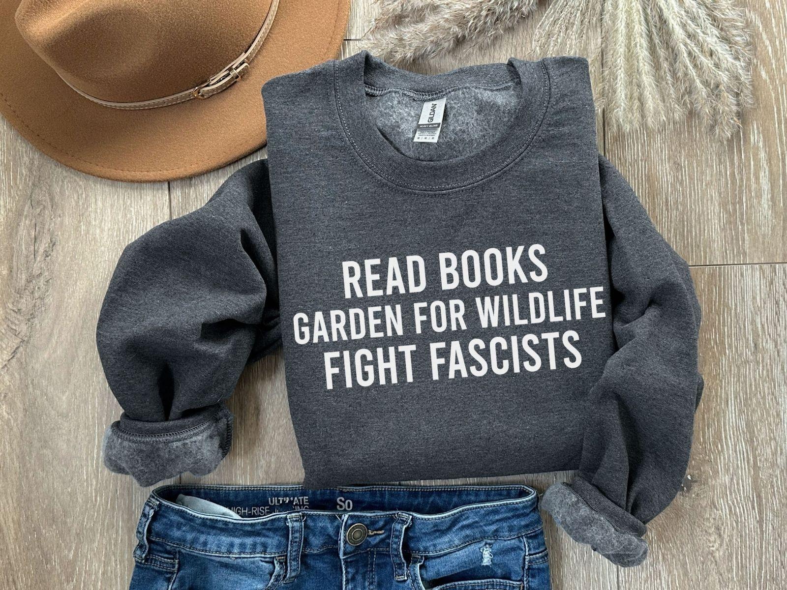 A Gildan 18000 sweatshirt with the saying "Read books garden for wildlife fight fascists"