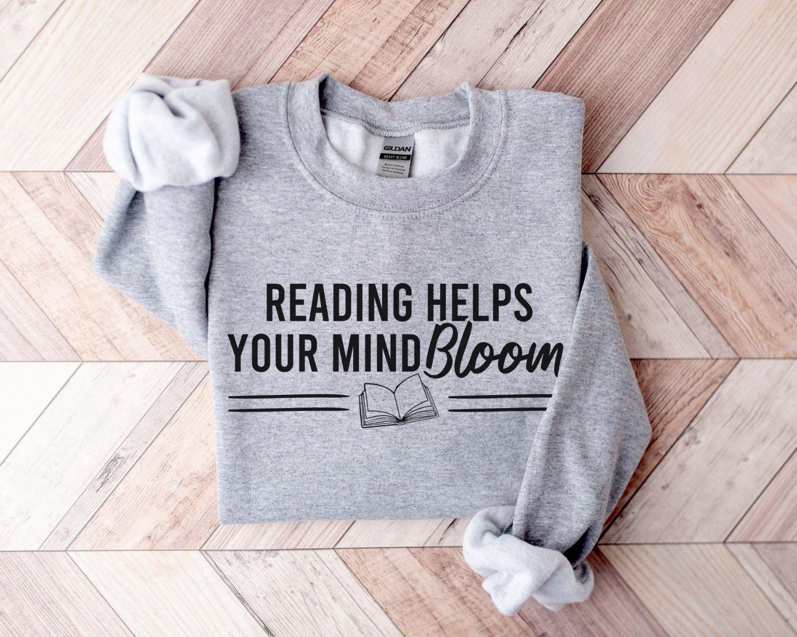 A Gildan 18000 sweatshirt with the saying "reading helps your mind bloom"