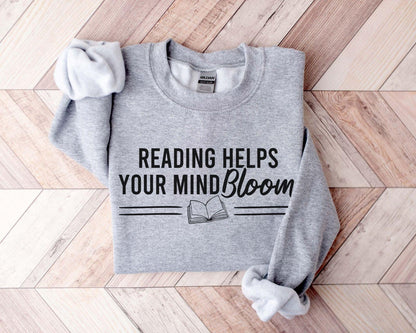 A Gildan 18000 sweatshirt with the saying "reading helps your mind bloom"
