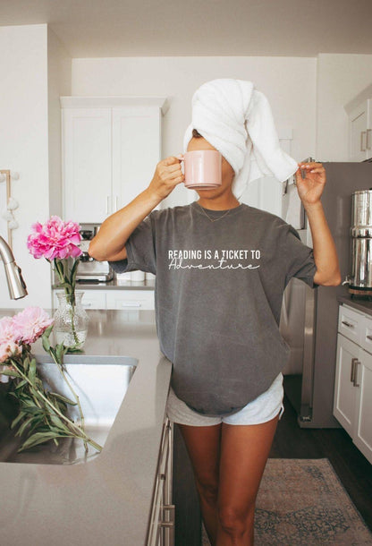 A comfort colors® shirt with the saying "Reading is a ticket to adventure"