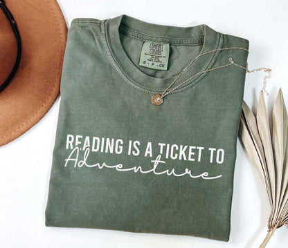 A comfort colors® shirt with the saying "Reading is a ticket to adventure"