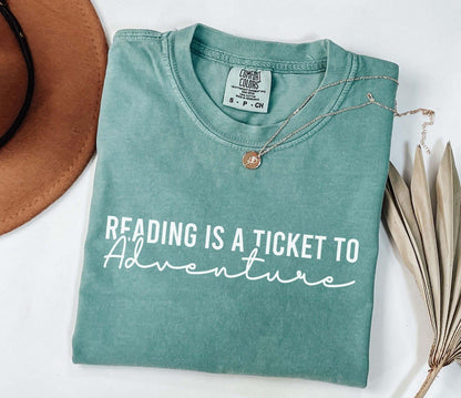 A comfort colors® shirt with the saying "Reading is a ticket to adventure"