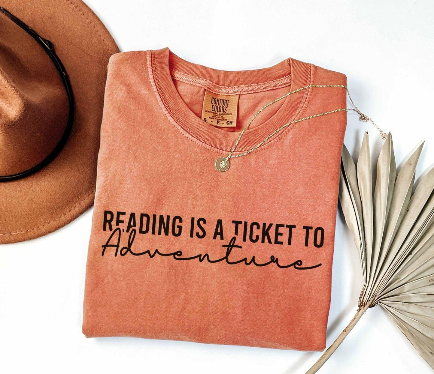 A comfort colors® shirt with the saying "Reading is a ticket to adventure"