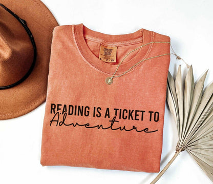 A comfort colors® shirt with the saying "Reading is a ticket to adventure"