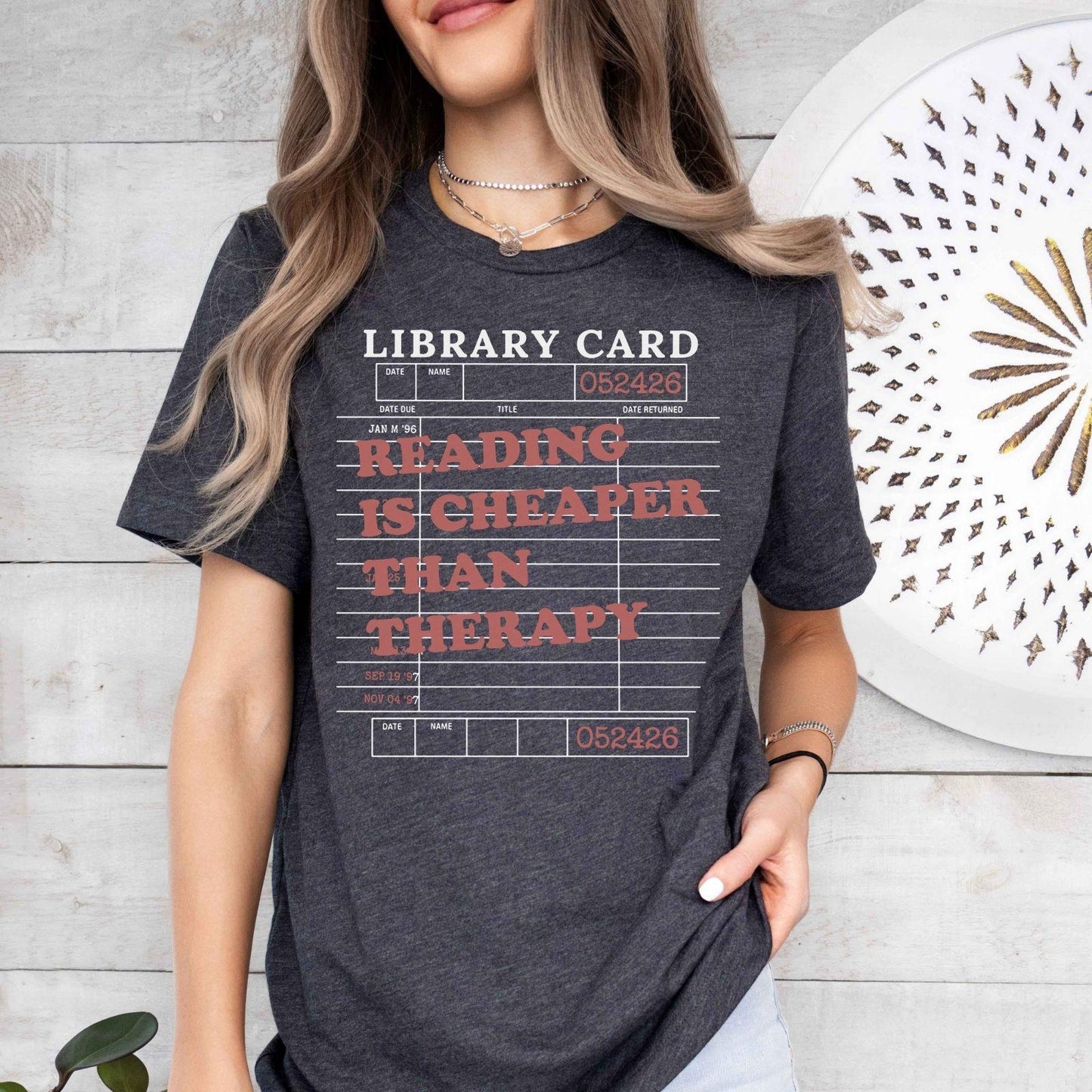 A bella canvas 3001 shirt with the saying "Reading is cheaper than therapy"